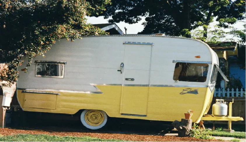 a small travel trailer parked outside home