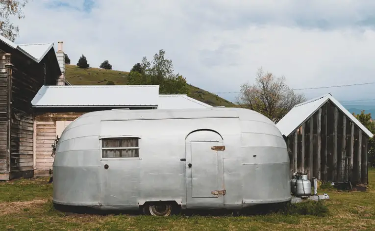 an old airstream trailer parked in front of house