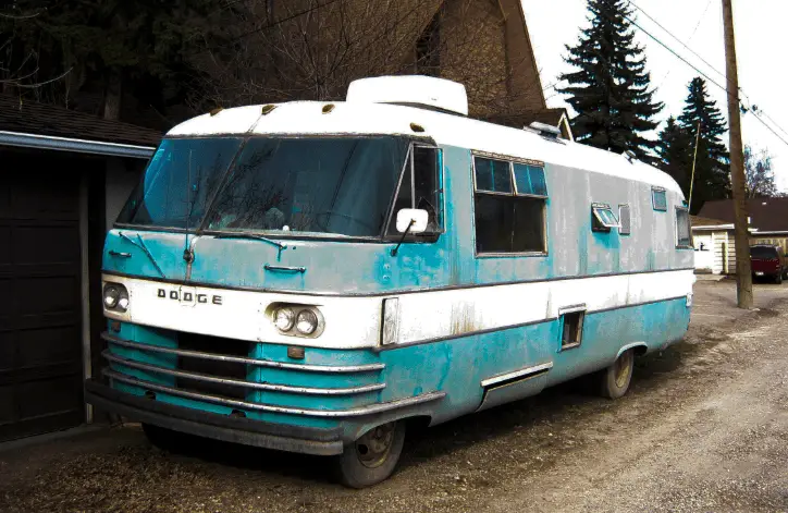 an old rv parked in-front of house