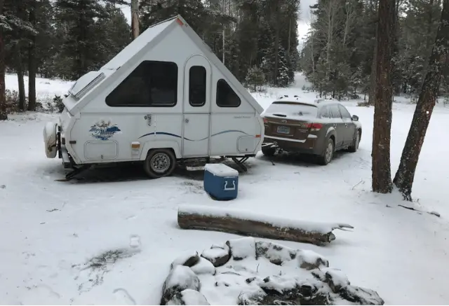 a car towing a aliner camper in snow